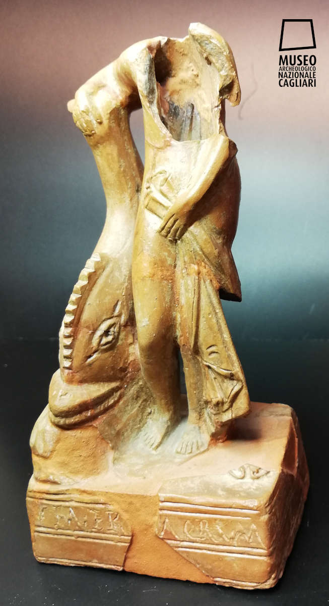 Statuina di Venere con delfino, frammentata all’altezza del busto e quindi acefala. Rappresenta una figura femminile nuda, stante frontalmente, che si appoggia con il braccio destro alla pinna di un delfino posto su una roccia.